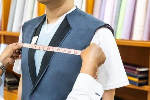 Close-up of professional tailor measuring client body with measuring tape to Stock Photos