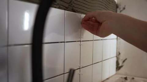 Close-up of professional tiler worker hand installing white ceramic tile spacer Stock Footage 344564726