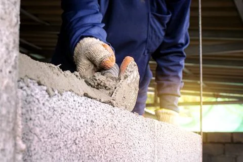 Close-up of a professional worker using a pan knife to build a brick wall w.. Stock Photos