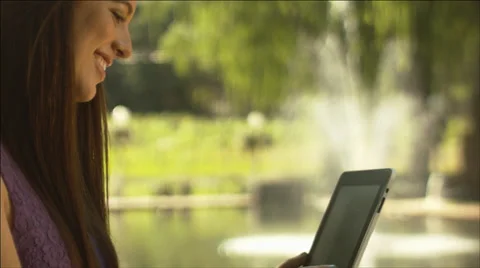 Close up profile of a beautiful girl using a digital tablet at a table outdoors Video stock 34437313