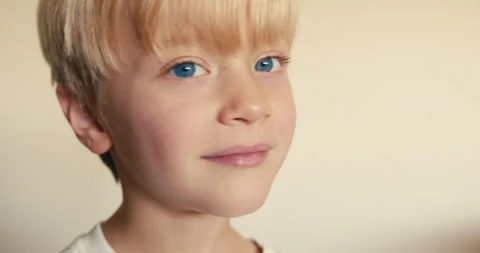 A close-up profile of a fair-haired, blue-eyed boy who shows his ear, then turns Stock Footage 324766514