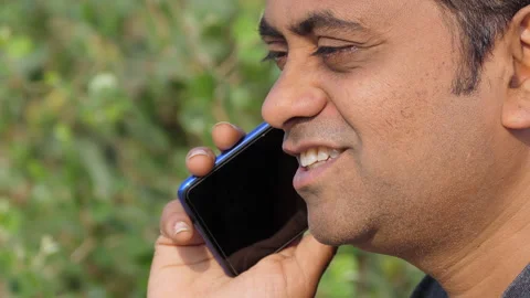 Close profile shot of a middle aged indian man happily talking over phone Stock Footage 148456204