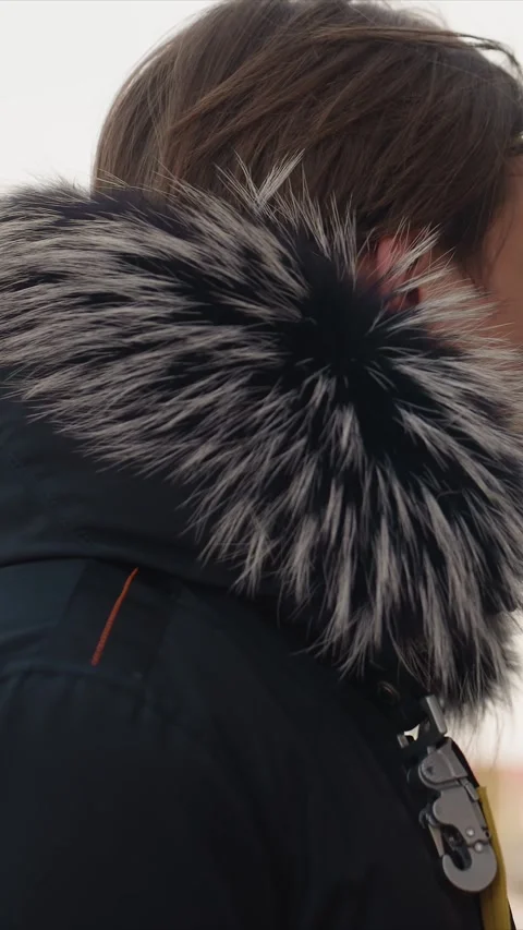 Close up profile shot of young man wearing black jacket with fur lined hood and Stock Footage 345545419