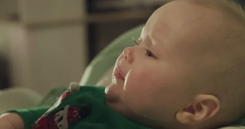 Close profile view of cute toddler in chair during feeding with spoon by mother Stock-Footage 147219102