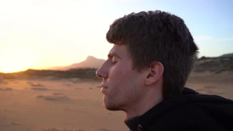 Close-up of the profile of a young man taking deep breaths and meditating sit Stock Footage 218255013
