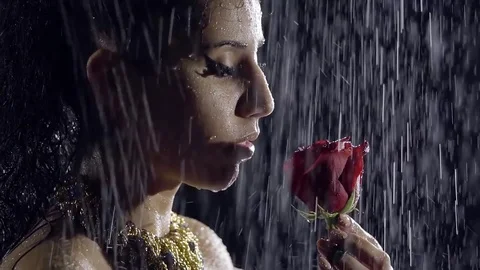 Close-up. Profile of a young Oriental girl at night under heavy rain. She inhale Stock Footage