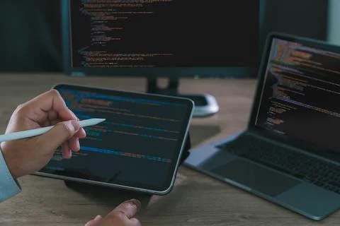 Close-up of programmer freelance working on tablet and laptop with code on .. Stock Photos