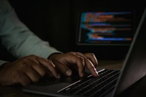 Close-up of programmer typing code on laptop with blurred screen of program.. 写真素材