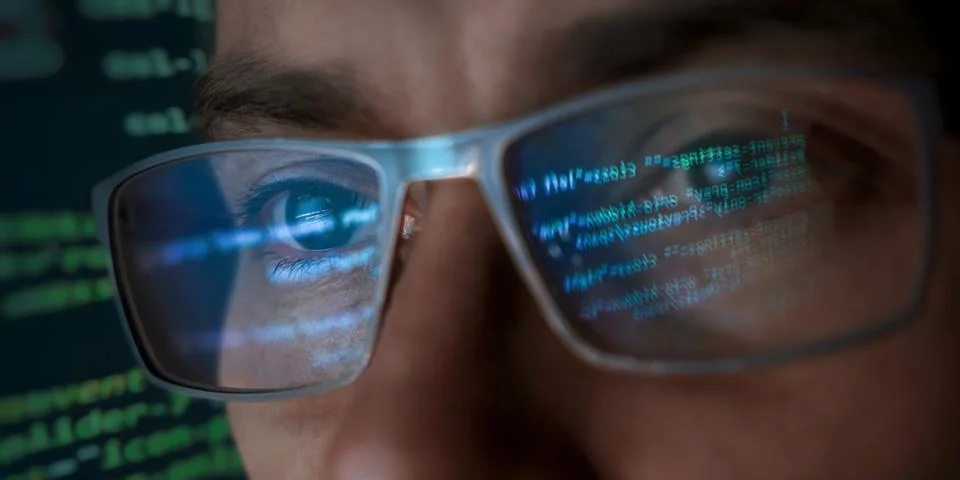 Close-up of programmer's face wearing eyeglasses reflecting programming code Stock Photos