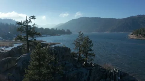 Close proximity drone flight backwards revealing trees atop island in a lake 4K Stock Footage 150200073