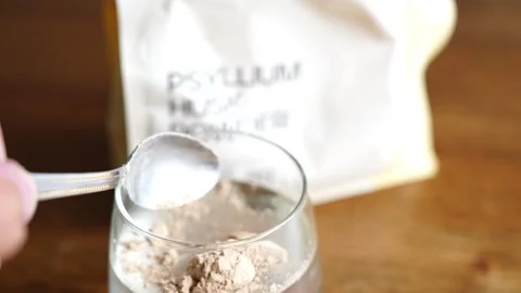 Close up of psyllium husk powder being added to a glass of water and stirred Stock Footage 334963293