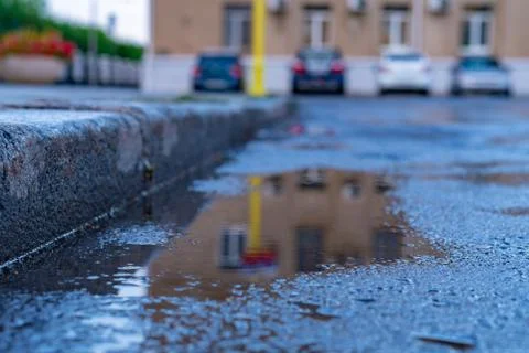 Close up puddle on the asphalt with reflections after the rain in city Foto stock