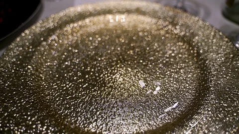 Close up pull back view of decorative gold glitter shiny plate at table Stock Footage 100604865