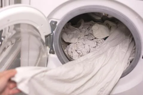 Close-up of pulling out white linen from the washing machine Stock Photos
