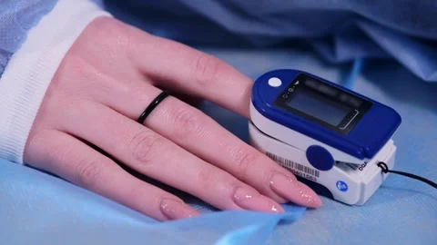 Close-up of pulse oximeter tracking on a patient's finger during surgery. Stock Footage 265014035