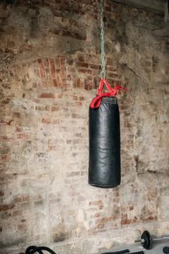 Close up of punching bag in loft style gym with brick wall and sports equipment Stock Photos