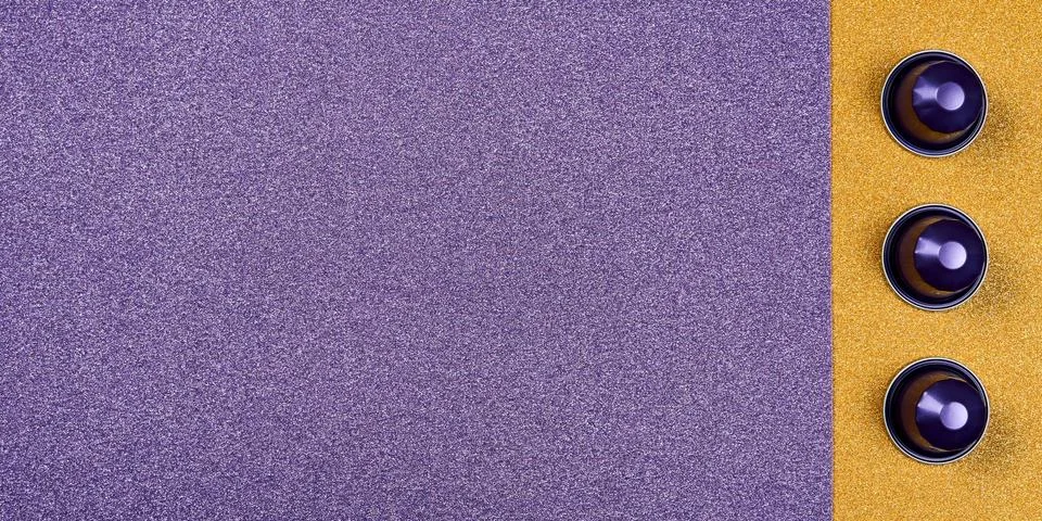 Close up of purple coffee capsules on glittery purple and gold background. Stock Photos