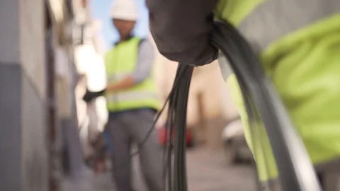 Close-up push-in shot of two technicians pulling out an optical fiber cable Видео 114193356