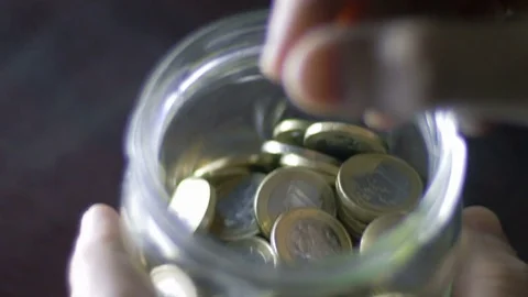 Close-up of putting a coin into a jar full of savings at home Stock Footage 75545837
