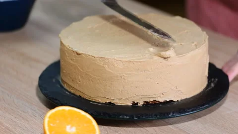 Close-up of putting cream on a chocolate sponge cake. Home baking. Cake on a Stock Footage 122070631