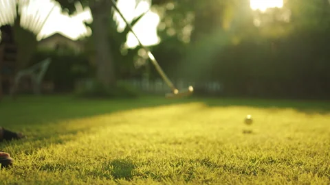 Close up putting golfball going to into hole in garden in background at sunset. Stock Footage 143714339
