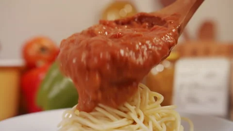Close up of Putting meat sauce over spaghetti, pasta on a plate. Video stock 130665477
