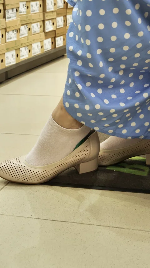 Close-up of putting shoe with heel on toe. Racks with large selection of shoes 動画素材 274877072