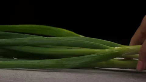 Close up of putting spring onions onto table on black background Stock Footage 277682316