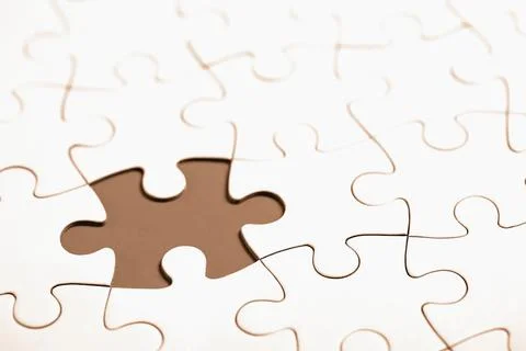 Close-up of a puzzle piece missing from a white jigsaw puzzle 스톡 사진