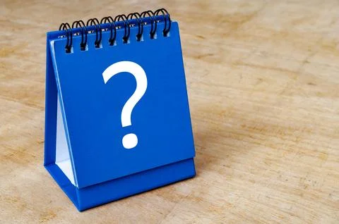 Close up of question mark on blue notepad on wooden background. Question an.. Foto stock