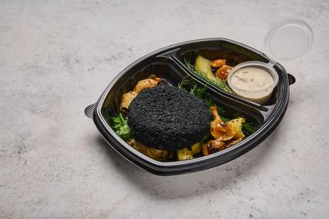 Close up rabbit cutlet in black breading in baby potatoes, spinach, sauce Stock Photos