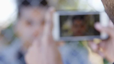 Close Up - Rack focus from a phone camera to Indian man posing behind a Stock Footage 125091936