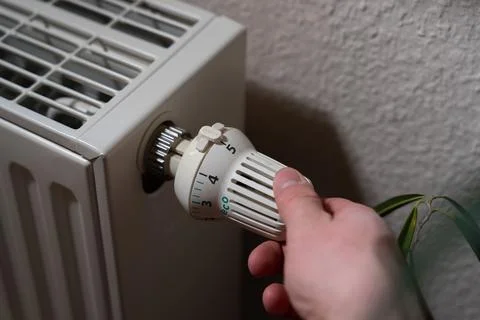 Close-up of a radiator, a hand is setting the highest level of energy 写真素材