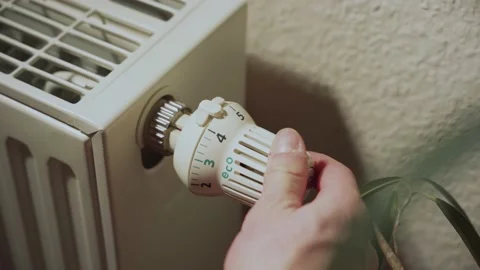 Close-up of a radiator, a hand is turning it down to the eco level Stock Footage 236010383