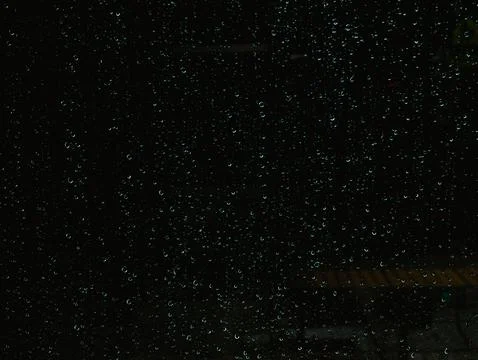 Close-Up of Rain Droplets on Dark Window Glass at Night with Bokeh Lights Foto stock
