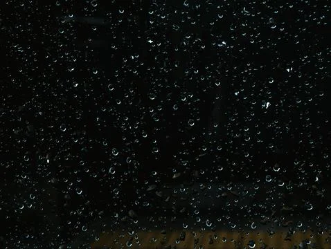 Close-Up of Rain Droplets on Dark Window Glass at Night with Bokeh Lights 스톡 사진