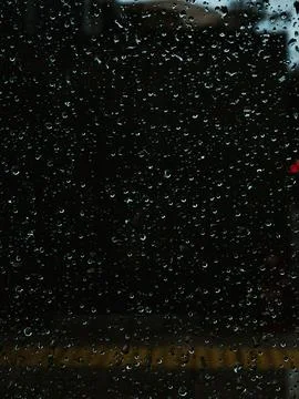 Close-Up of Rain Droplets on Dark Window Glass at Night with Bokeh Lights Foto stock