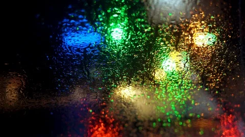 Close up rain drops on car window glass with blurred night city car lights bokeh Stock Footage 103942524