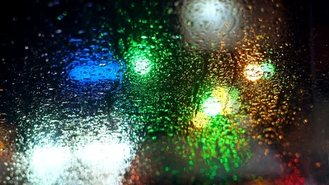 Close up rain drops on car window glass with blurred night city car lights bokeh Vidéo 104659854