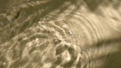 Close-up rain drops falling and splashing in water, leaf shadow on sand texture Stockbeeldmateriaal 251112028
