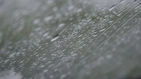 Close-up of rain drops splashing against a window glass with light leaks. Stock Footage 108985745