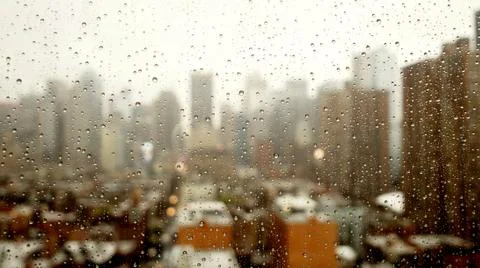 Close up of rain drops on window with cityscape skyline view Stock Photos