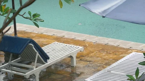 Close up of rain falling on sun bed and swimming pool at hotel Bali Indonesia Stock Footage 84172717