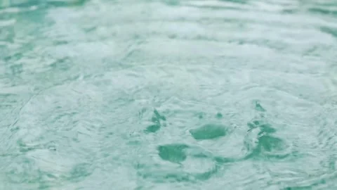 Close up rain water drops falling into water surface in swimming pool, Rain.. Stock Footage 337007708