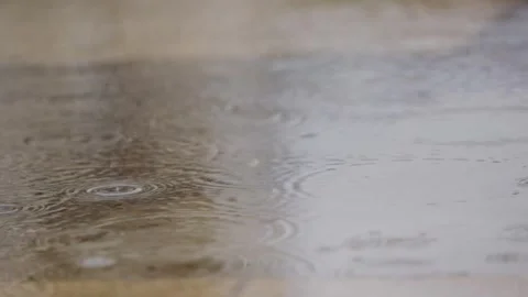 Close up on rain water puddle as raindrops fall and make ripples in winter Stock Footage 293706271