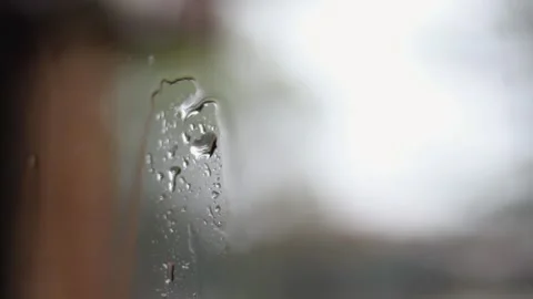 Close-up rain on window pane glass with defocused outdoor bokeh Видео 331112087