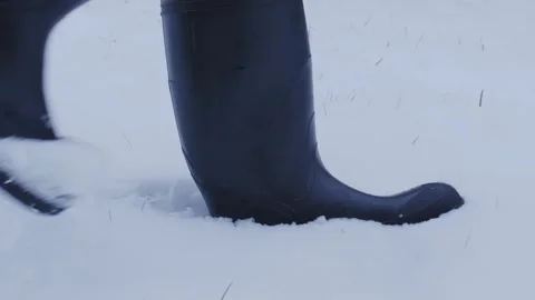 Close up of rainboots walking through several inches of snow Video stock 250422230
