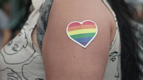 Close-up of a rainbow heart-shaped sticker on the shoulder of a Pride parade Stock Footage 346238875