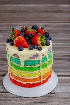 Close up of rainbow sponge cake decorated with fresh berries. Stock Photos