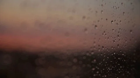 Close-up of raindrop on window glass behind which red sunset Stock Footage 91365773